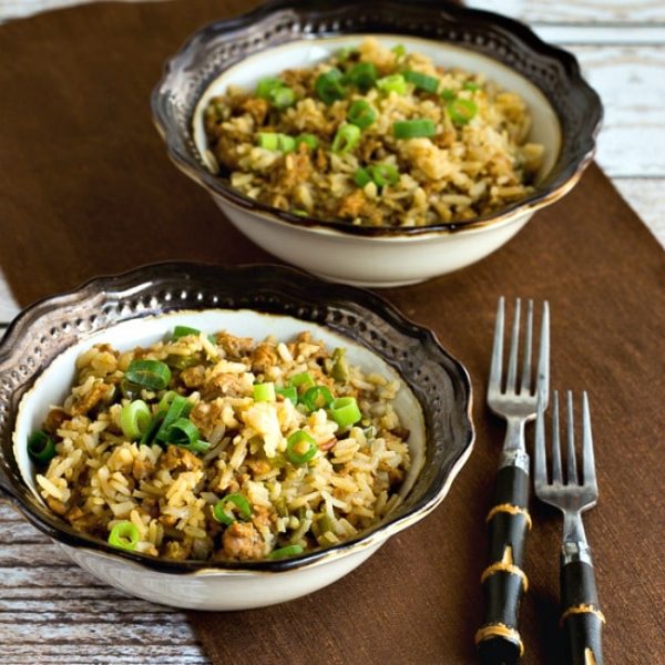 square image for Slow Cooker Spicy Brown Rice with Sausage and Peppers shown in two serving bowls with forks