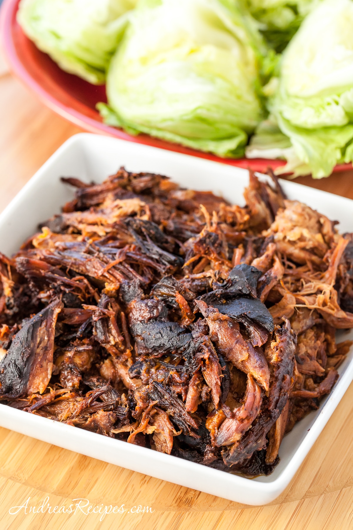 Slow Cooker Char Siu Pork Lettuce Wraps from Andrea Meyers with pork in bowl and lettuce leaves in background