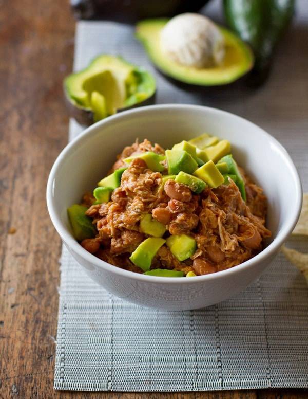 Crockpot Mexican Chicken from Pinch of Yum, shown in bowl with avocado.