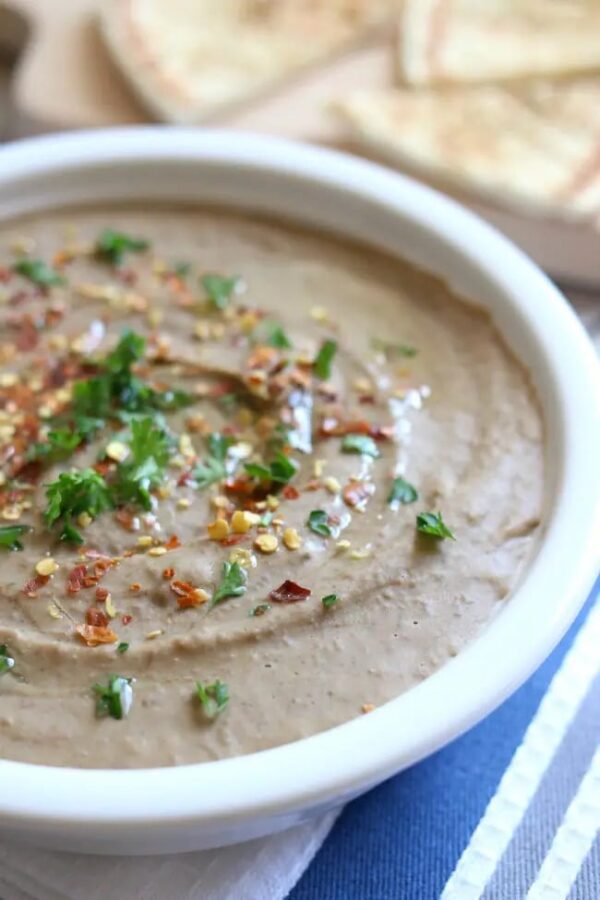 Slow Cooker Garlic Lentil Hummus shown in bowl with pita bread.