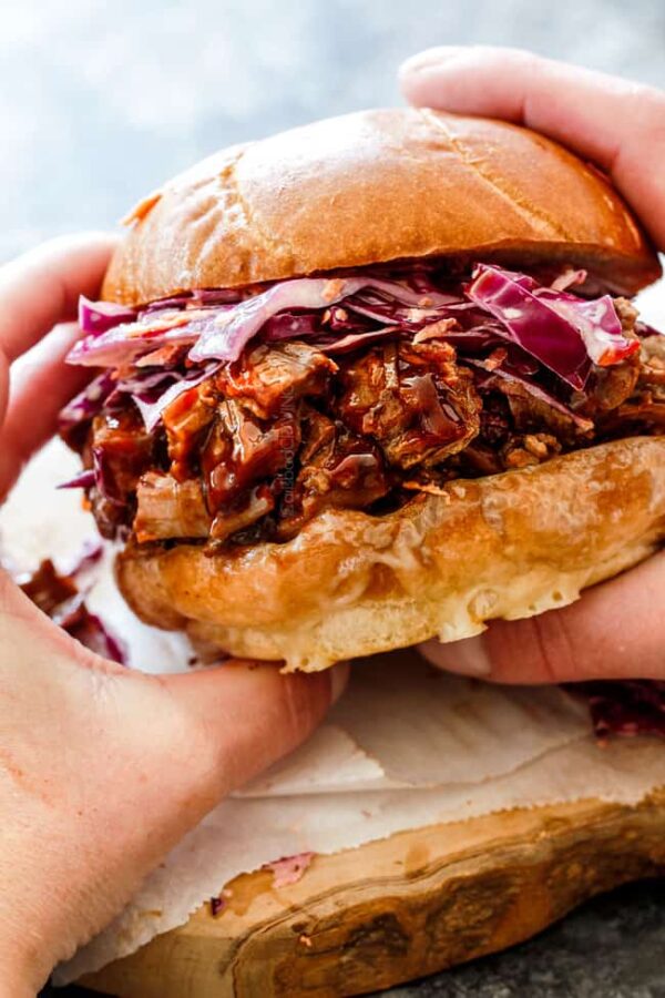 BBQ Brisket Sandwiches with Coleslaw from Carlsbad Cravings shown with someone holding sandwich.