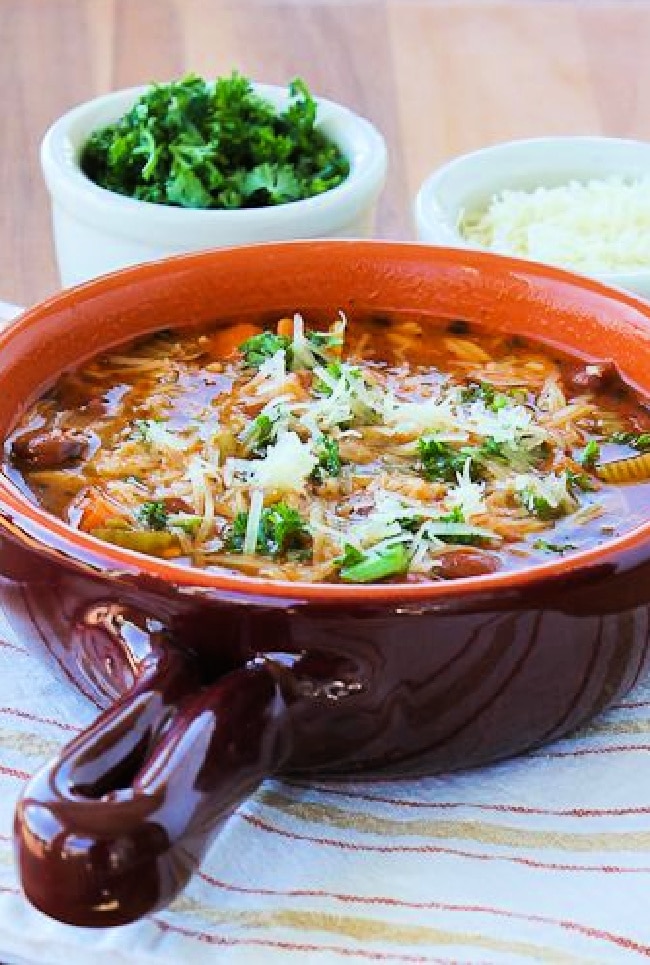 Slow Cooker Pasta e Fagioli Soup show in bowl with Parmesan and herb garnish.