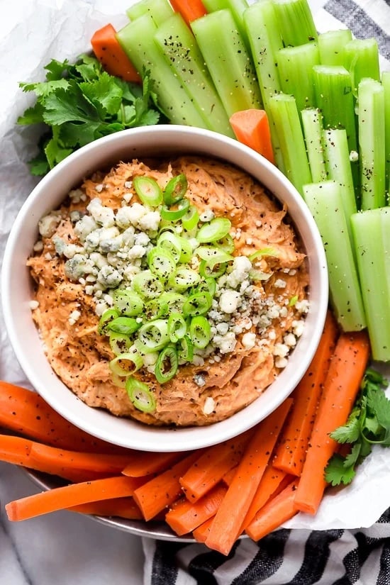 Slow Cooker Buffalo Chicken Dip from Skinnytaste shown in bowl with carrots and celery.