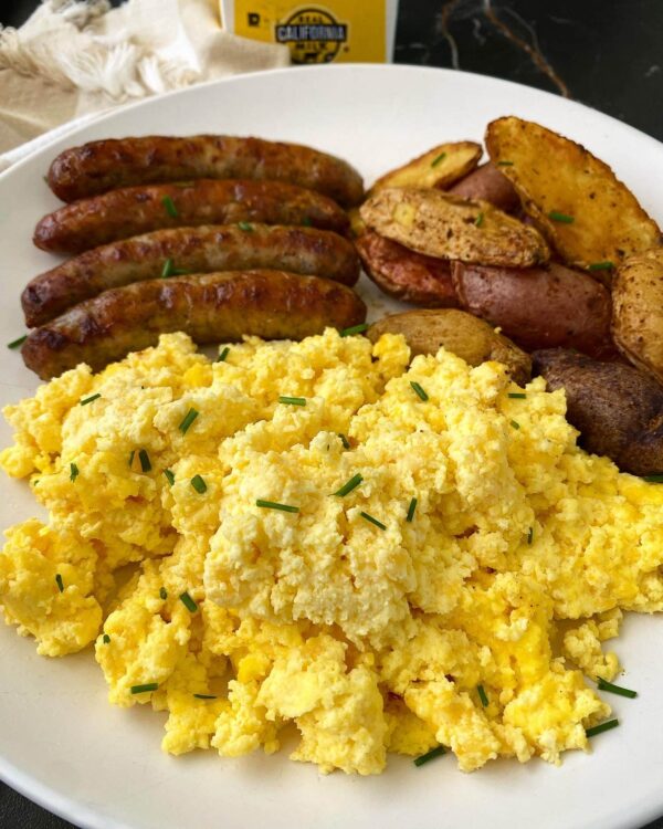 Slow Cooker Scrambled Eggs shown on plate with sausage from Fit Slow Cooker Queen