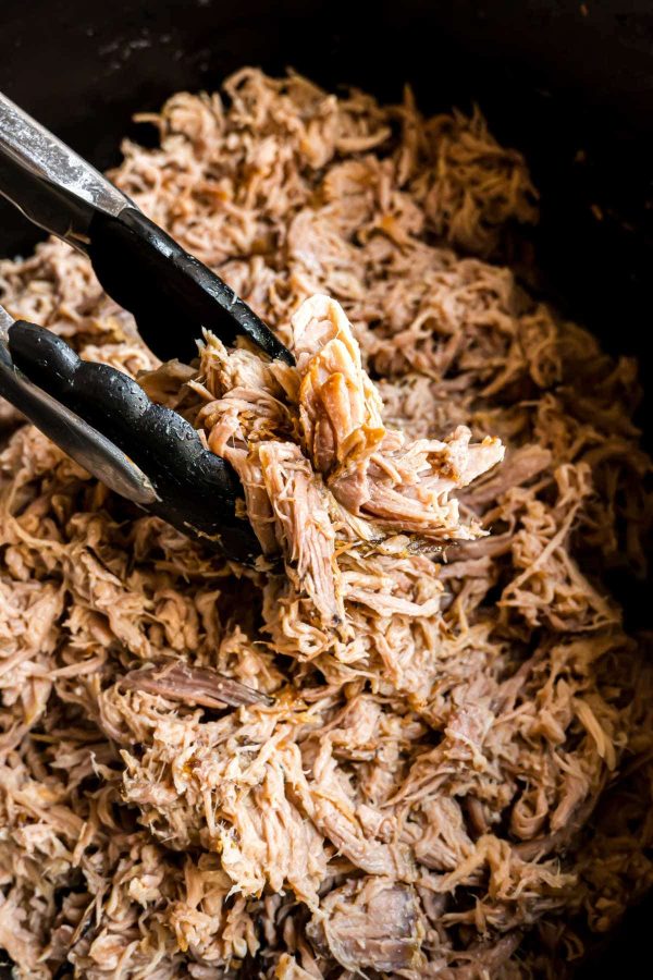 Slow Cooker Kalua Pork from Shugary Sweets, shown shredded apart in CrockPot.